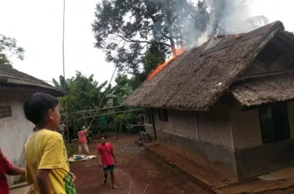 Warga berusaha memadamkan api yang menyala di atap bangunan rumah korban. (Ist).