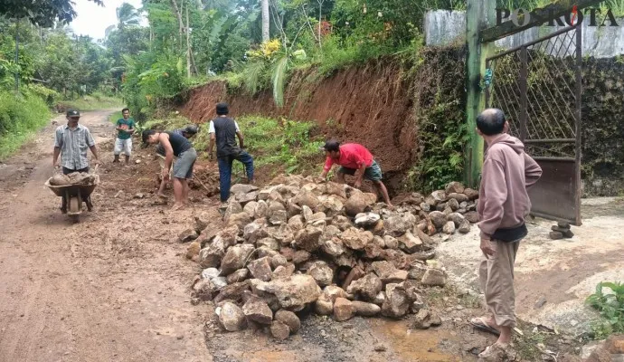 Sejumlah warga Tegalwangi membersihkan material tebing yang longsor dan menutupi jalan. (Foto: Samsul Fatoni)