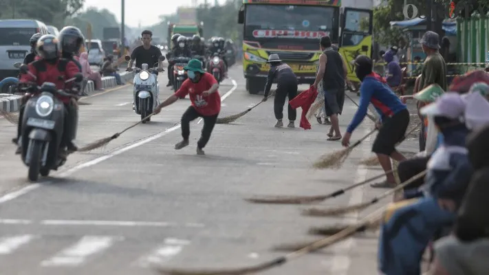 Aktivitas warga saat mengambil uang sedekah yang dilempar pemudik melintas di Jembatan Sewo, Jalur Pantura Sukra, Indramayu, Jawa Barat. (Poskota/Ahmad Tri Hawaari)