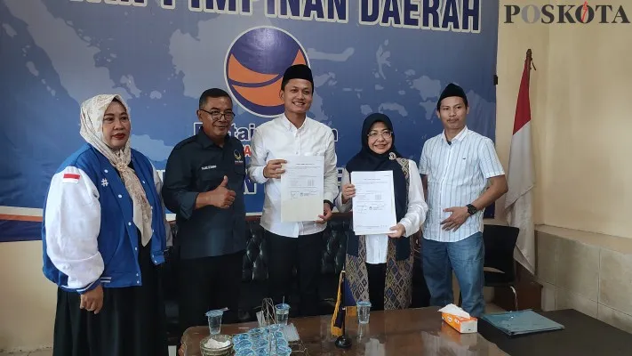 Pasangan Balon Bupati dan Wakil Bupati Pandeglang, Dewi-Iing saat menyerahkan formulir pendaftaran di DPC Nasdem. (Poskota/Samsul Fatoni)