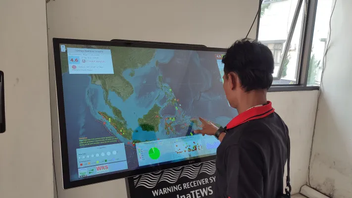 Seorang warga melihat monitor informasi bencana di Pandeglang. (Poskota/Samsul Fatoni)