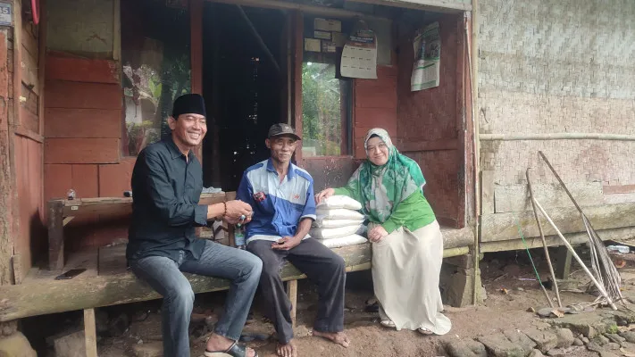 Dua anggota DPRD Pandeglang saat menyerahkan bantuan kepada Abun, guru ngaji yang rumahnya nyaris ambruk. (Poskota/Samsul Fatoni)