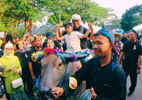 Pj Bupati Lebak Iwan Rusminto bersama putranya saat menunggangi salah satu hewan kerbau dalam parade. (dok. Disnakeswan Lebak)