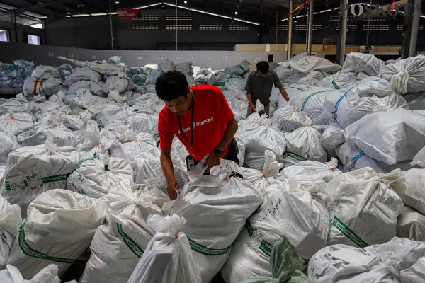Petugas saat menyortir paket barang yang dibungkus menggunakan dus kemasanuntuk sebelum dikirim ke pelanggan di salah satu perusahaan pengiriman barang, Kota Tangerang, Banten, Minggu, 22 Desember 2024. (Poskota/ Ahmad Tri Hawaari)