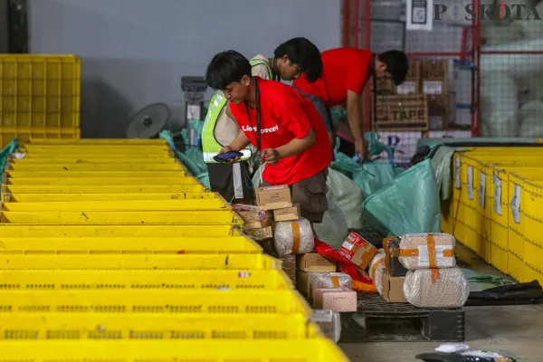 Petugas saat menyortir paket barang yang dibungkus menggunakan dus kemasanuntuk sebelum dikirim ke pelanggan di salah satu perusahaan pengiriman barang, Kota Tangerang, Banten, Minggu, 22 Desember 2024. (Poskota/ Ahmad Tri Hawaari)