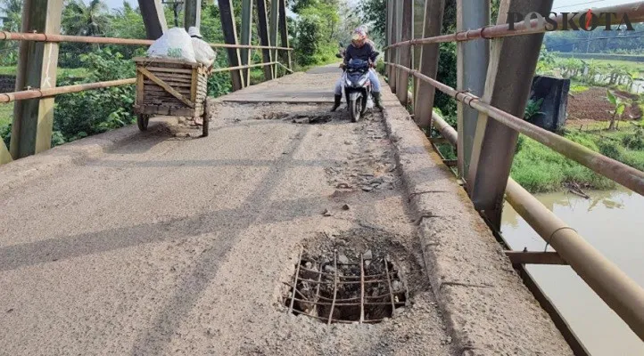 Pengendara saat melintas di jembatan Surianen di Pandeglang bolong dan memprihatinkan. (Foto: Samsul Fatoni).