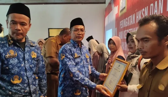 Kepala Dinsos Pandeglang saat memberikan piagam penghargaan kepada peserta PKH yang graduasi. (Foto: Samsul Fatoni).