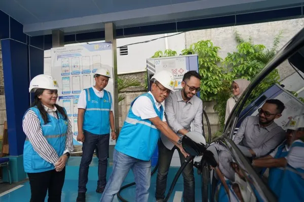 Foto: General Manager PLN Unit Indik Distribusi Jakarta, Lasiran membantu pengendara mobil listrik yang sedang mengisi baterai kendaraannya di SPKLU Rest Area KM 6B Tol Jakarta - Cikampek. (Dok. PLN)