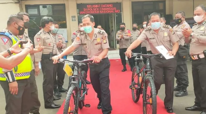 Kapolsek Cimanggis Kompol Ibrahim Joao Sadjab dengan Wakapolsek AKP Mare Mare memberikan masing-masing anggota purnawirawan sepeda gunung sebelum dilepas melewati karpet merah. (Angga)