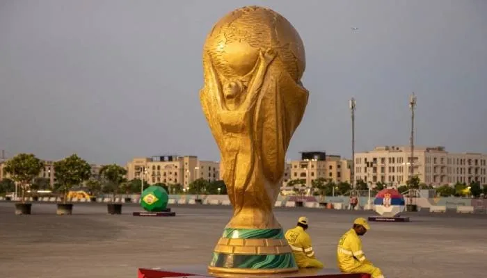 Pekerja duduk di samping replika Piala Dunia di luar Stadion Lusail Qatar pada 10 November 2022.