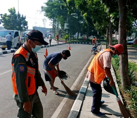 Seorang warga sedang diberi sanksi sosial membersihkan sampah akibat tak terapkan prokes. (foto: istimewa)