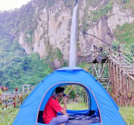 Salah satu pengunjung sedang menikmati keindahan alam Curug Ngebul di tenda area berkemah (Instagram/@visitcianjur)