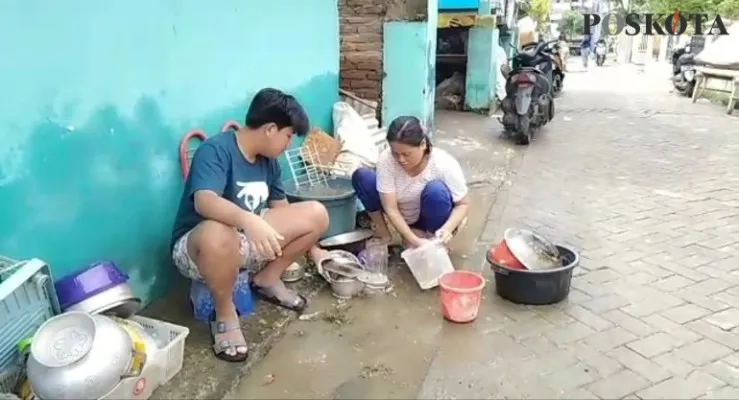 Warga tengah memberihkan peralatan rumah tangga dari sisa endapan lumpur. (yusuf)