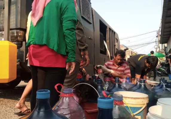 Warga Bekasi antre air bersih yang disalurkan Polres Bekasi Kota dengan water cannon. (Ihsan)