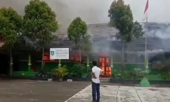 Salah seorang warga hanya dapat melihat kobaran api yang membakar gedung SDN Ukirsari. (ist)