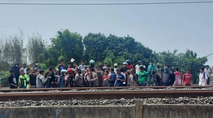 Warga dan petugas mengevakuasi pria tanpa identitas yang tewas tertabrak kereta di perlintasan dekat Stasiun Buaran, Jaktim.