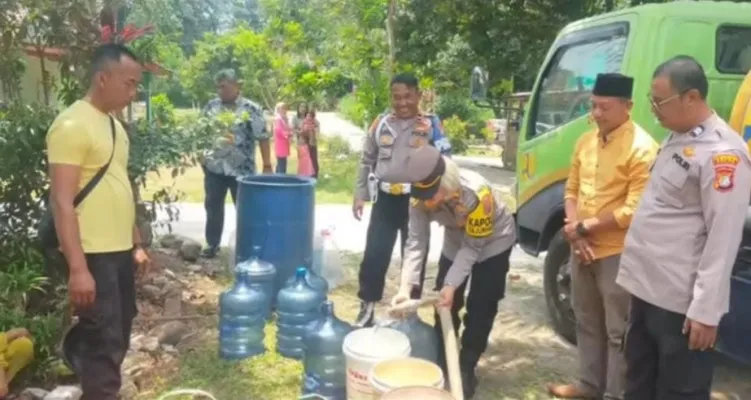 Kapolsek Tajurhalang Iptu Tamar membagikan air bersih ke galon-galon yang telah disediakan warga di Desa Kampung Jampang. (Ist)