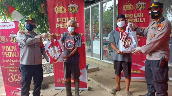 Kapolsek Sawangan AKP M. Meltha Mubarak bersama Wakasat Binmas Polres Metro Depok AKP Imam Suyono membagikan bansos kepada warga usai divaksin (angga)