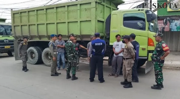 Petugas saat sedang memberhentikan truk yang tak patuh jam operasional. (Foto/Veronica)