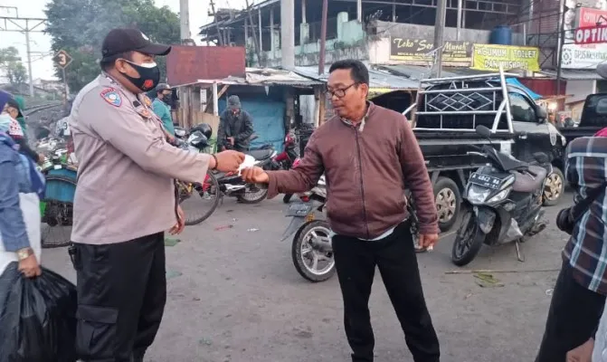 Personil Polsek Rangkasbitung membagikan masker kepada para pengunjung dan pedagang di pasar Rangkasbitung. (Foto/yusuf)