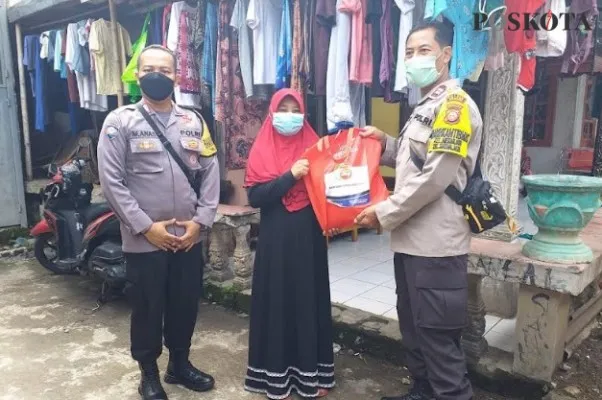 Anggota Bhabinkamtibmas Kelurahan Cilodong Aipda Anas dan Priyo membagikan paket sembako ke warga membutuhkan (angga)