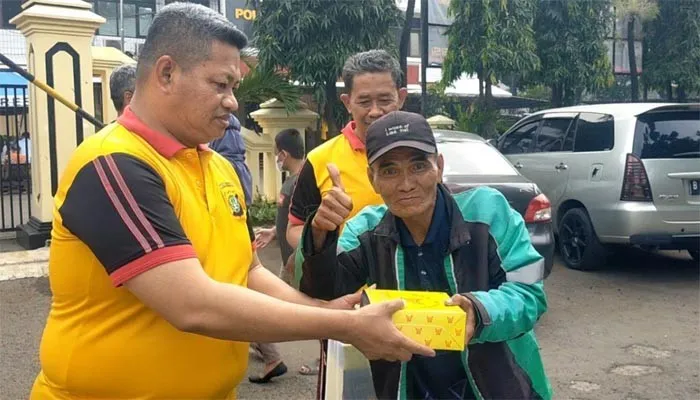 Kapolsek Kalideres AKP Syafri Wasdar bersama anggota bagi-bagi makanan dan bakti sosial bersih lingkungan depan mako Polsek. (ist)