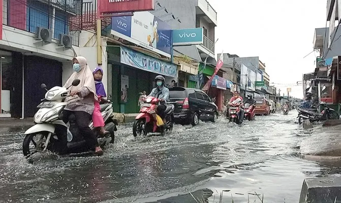 Para pengendara yang melintasi banjir setinggi 50 cm, akibat hujan di Jalan raya pondok ungu permai Bekasi. Senin (18/10/2021) pagi. (Foto/if)