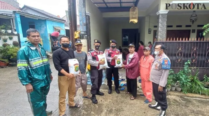 Anggota Polsek Bojongsari menyerahkan bantuan  sembako kepada Ketua RW 12 Kiswanto dengan disaksikan Ketua LPM di lokasi banjir yang sudah mulai surut. (Angga)