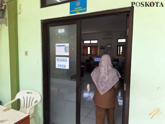 Salah seorang guru masuk ke ruangan tempat orang tua melakukan proses input data pendaftaran PPDB di SMPN 7 Kota Bekasi. (Poskota.co.id/Ihsan Fahmi)