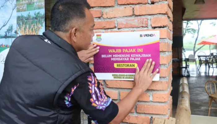 Petugas pajak saat memasang stiker di lokasi wajib pajak. (Foto/ist)