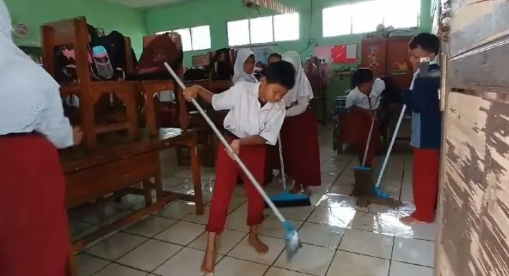 Siswa SDN Sukamanah 2 Jonggol bersihkan kelas yang kebanjiran.(Ist)