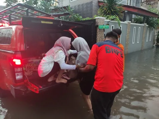 Petugas BPBD Kota Bekasi saat mengevakuasi warga melewati genangan banjir. (Dok: Humas BPBD Kota Bekasi)