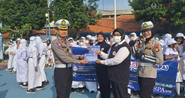 Kasat Lantas Polres Metro Depok Kompol Multazam didampingin Kanit Kamsel AKP Elly memberikan buku Road Safety Partnership Action kepada siswa. (Angga)