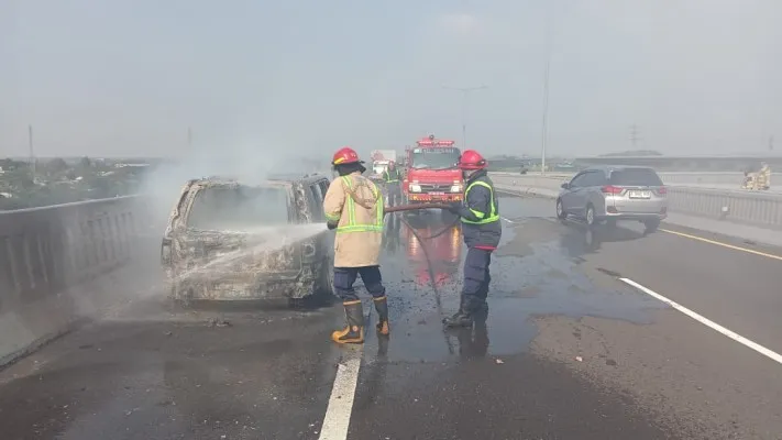 Petugas Damkar saat memadamkan api di badan mobil Nissan Xtrail yang terbakar di Tol MBZ, KM 34 Cikampek. (Dok: Damkar Kabupaten Bekasi)