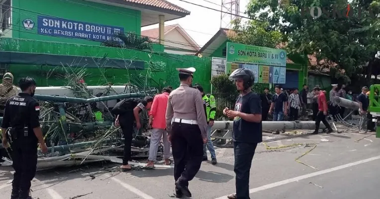 Para petugas kepolisian dan relawan saat mengevakuasi jatuhnya tiang provider telekomunikasi akibat Ditabrak truk di depan SDN II dan III Kota Baru, Bekasi Barat. Rabu (31/8/2022) lalu. (Ihsan Fahmi).