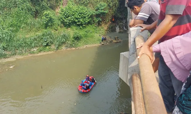 Warga berkerumun melihat proses evakuasi jalannya pencarian korban yang terjun ke sungai Ciliwung. (Foto/angga) 