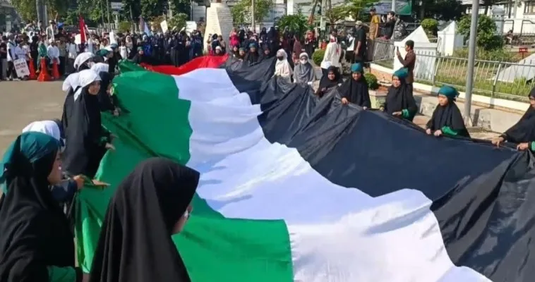 Bendera raksasa Palestina saat dibentangkan oleh ratusan masa di Pandeglang. (Foto: Ist).