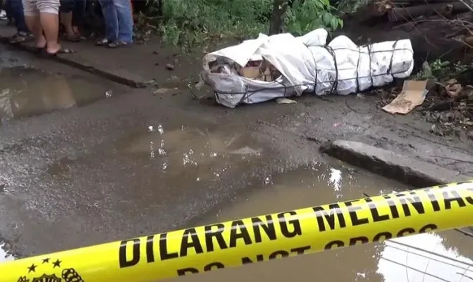 Sesosok mayat wanita terbungkus spanduk dan kardus ditemukan di tepi Jalan Raya Bekasi, Cakung, Jakarta Timur. (Foto/cr02) 