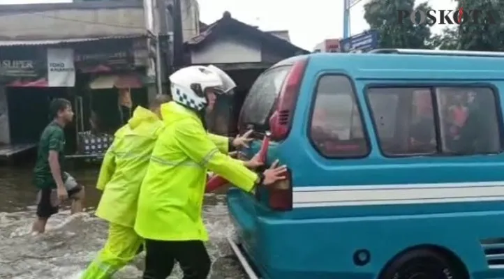 Kapolres Karawang, AKBP Wirdhanto Hadicaksono turun tangan bantu dorong kendaraan mogok akibat terjebak banjir.(aep)