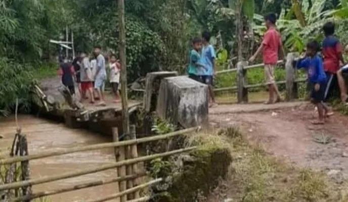 Warga  di jembatan kali Cimoyan Pandeglang  yang nyaris ambruk. ( Istimewa).