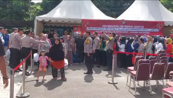 Warga Kecamatan Kalideres, Jakarta Barat (Jakbar) berburu sembako gratis yang digelar di halaman Polsek Kalideres. (Poskota.co.id/Pandi Ramedhan)