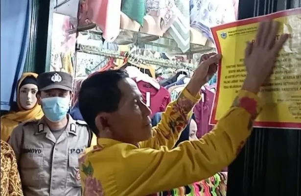 Kepala Diskoperindag Pandeglang, Suaedi Kurdiatna saat tempel stiker peringatan di kios pasar. ( Ist).