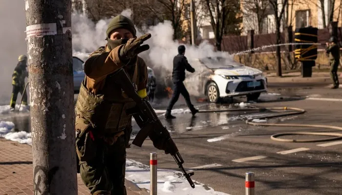 Pasukan Ukraina mengambil posisi di luar fasilitas militer saat dua mobil terbakar di sebuah jalan di Kyiv Ukraina pada Sabtu, 26 Februari 2022.