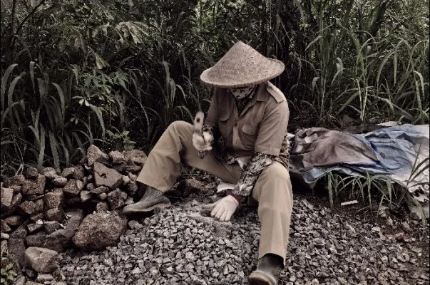 Kakek Marwan saat bekerja memecahkan puing batu. (Foto/Veronica)