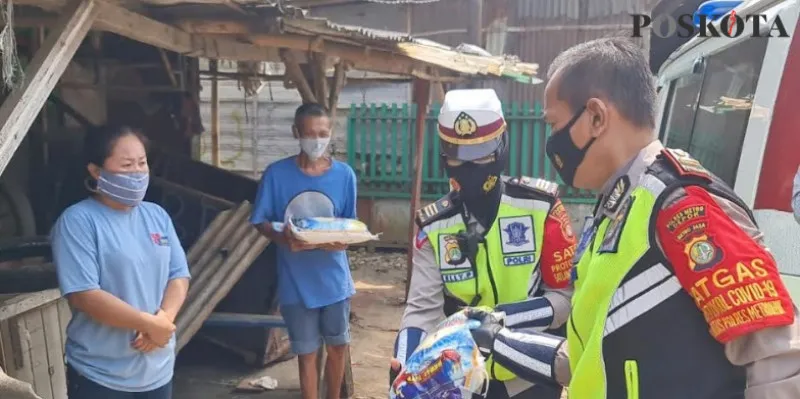 Kanit Kamsel AKP Elly bersama Ipda Ponco membagikan sembako door to door ke rumah pemukiman pemulung. (angga)