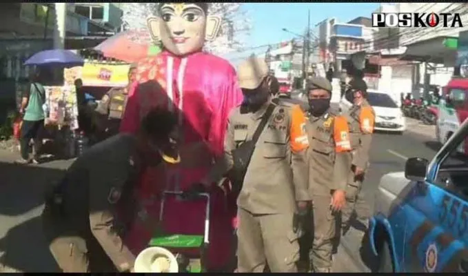 Petugas tengah menertibkan pengamen ondel-ondel yang tengah mencari uang di jalan. (dok)