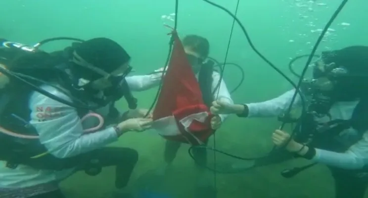 Tim penyelam saat proses pengibaran bendera merah putih di tengah laut. (Foto: Ist)