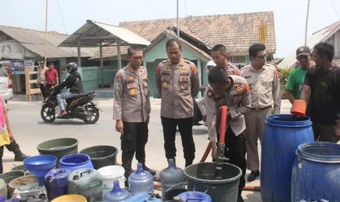 Personil Bidhumas Polda Banten saat membagikan 19.500 liter air bersih di Kampung Kebasiran. (ist)