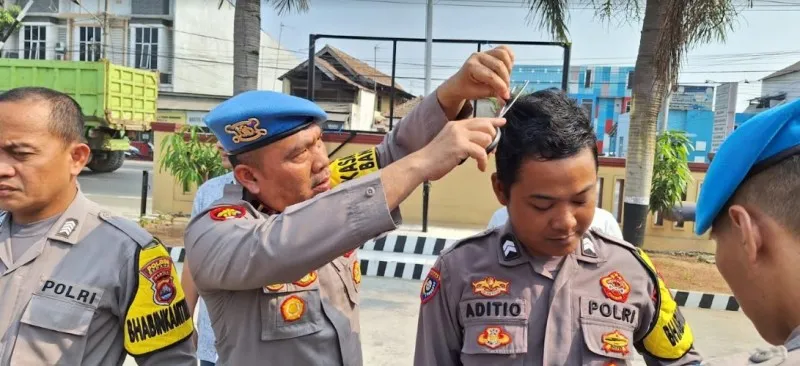 Kasi Propam Ipda P Rangkuti saat mencukur rambut anggota yang tidak rapi. (ist)