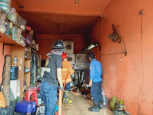 Petugas pemadam sedang memadamkan api di ruko laundry. (Ist).